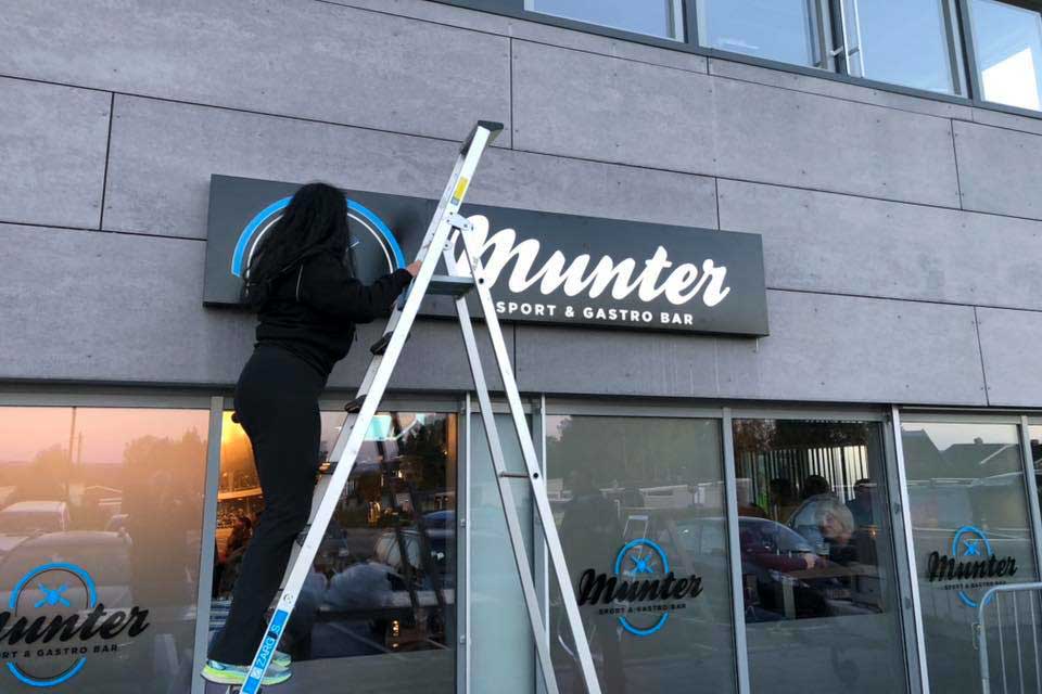 Medarbeider Tone monterer fasadeskilt hos Munter Bar og Gastropub